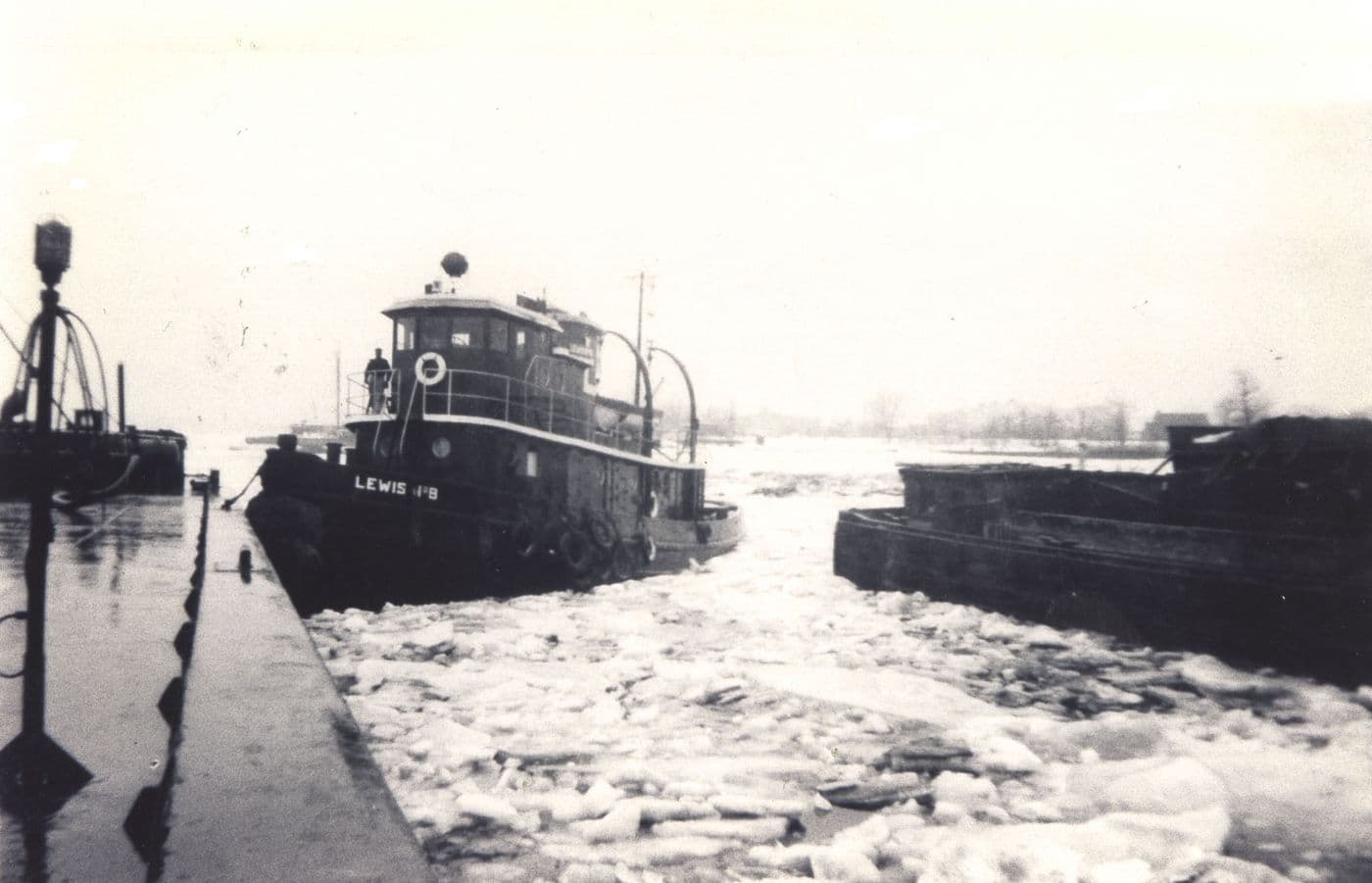 Lewis Oil tugboat number 8 and a barge surrounded by broken ice on Manhasset Bay
