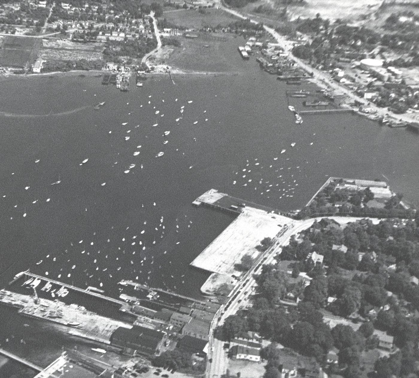 Aerial view of A and R Marshall Shipyard, Town Dock, Main Street, and boats moored across Manhasset Bay in March 1948